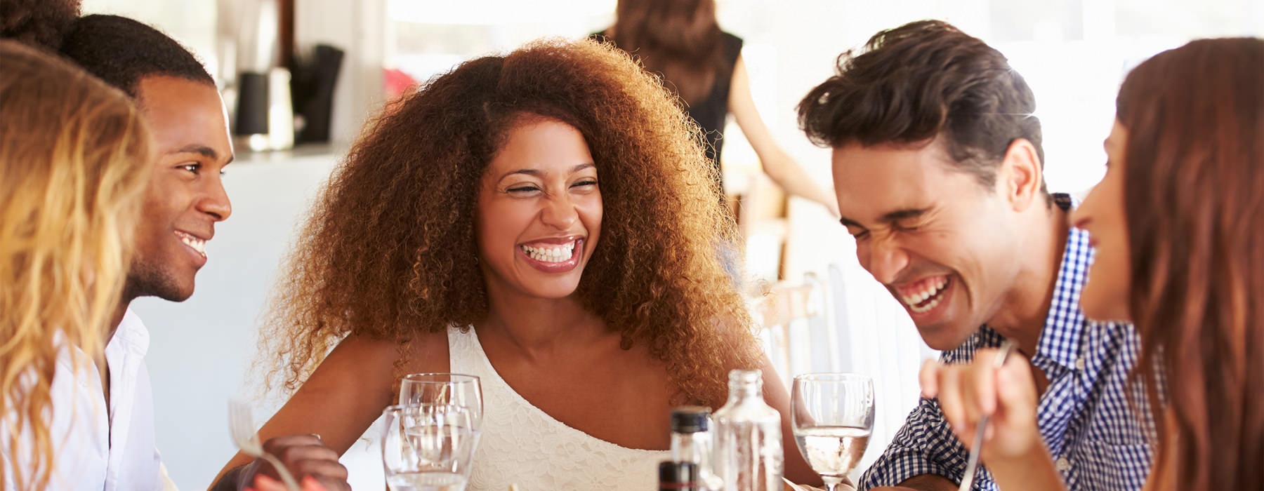 young friends laugh around a restaurant table
